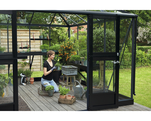 Gewächshaus mit Frau beim Pflanzen von Kräutern und Gemüse