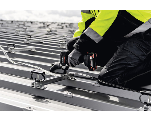 Artisan fixant une visseuse à batterie Metabo sur un toit métallique
