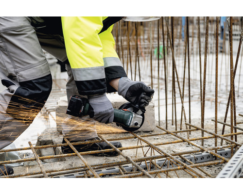 Ein Arbeiter schneidet mit einem Akku-Winkelschleifer Armierungseisen.