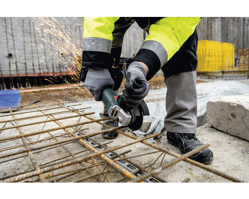 Mann schneidet Bewehrungsstahl mit einem Winkelschleifer auf einer Baustelle.