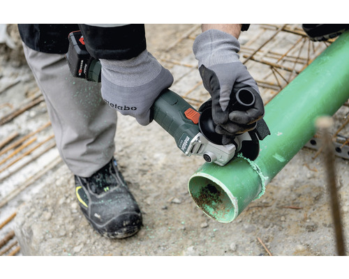 Eine Person schneidet mit einem Akku-Winkelschleifer ein Rohr.