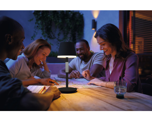 Scène avec une lampe de table éclairant un groupe de personnes sur une terrasse regardant une carte