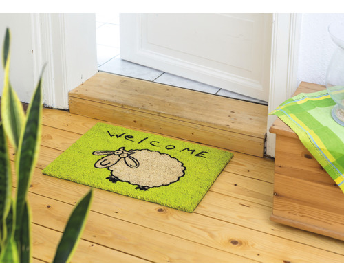 Fussmatte mit Schafmotiv und Willkommensgruss vor einer Tür