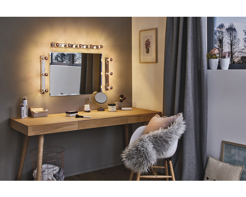 Pièce lumineuse avec coiffeuse, miroir avec éclairage et chaise avec coussins