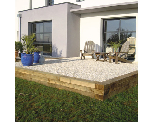 Terrasse avec bordure en bois, surface de gravier, mobilier de jardin et plantations devant une maison moderne