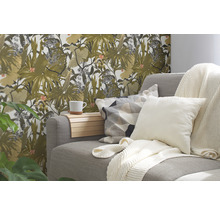 Wohnzimmer mit grauer Couch, Kissen, Decken und einer Wand mit floraler Tapete.