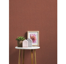 Nahaufnahme einer Wand mit Textiltapete, dekoriert mit einem Tisch, einer Zimmerpflanze und einem Bilderrahmen.