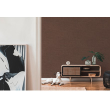 Wohnzimmer mit brauner Textiltapete, Kommode, Dekoration und einem Hund