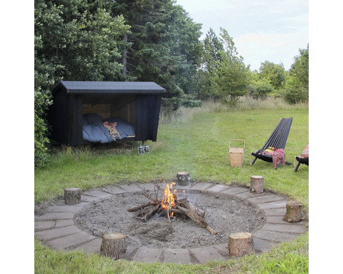 Extérieur avec foyer, souches d''arbres servant de sièges et cabane de couchage