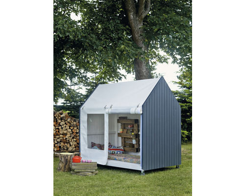 Spielhaus im Garten mit Holzstapel und Baum im Hintergrund