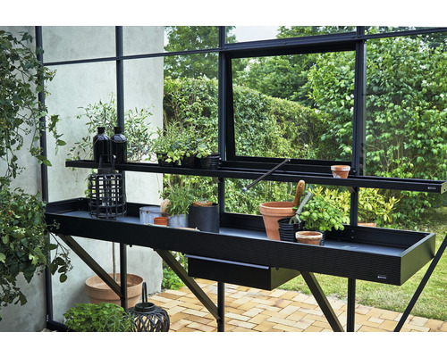 Table de jardin avec plantes et accessoires de jardin dans une serre