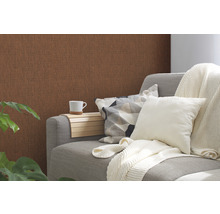 Wohnzimmer mit brauner Struktur Tapete, grauer Couch, Kissen und Getränkehalter