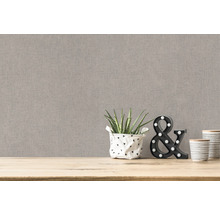 Nahaufnahme einer beigen Textiltapete mit Deko-Elementen auf einem Holztisch