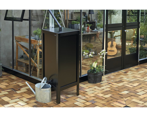 Collecteur d''eau de pluie noir avec arrosoir devant la serre