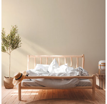 Helles Schlafzimmer mit Holzbett, Zimmerpflanze und Strohhut