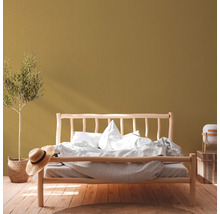 Schlafzimmer mit Holzbett, Zimmerpflanze, Strohhut und Holzboden