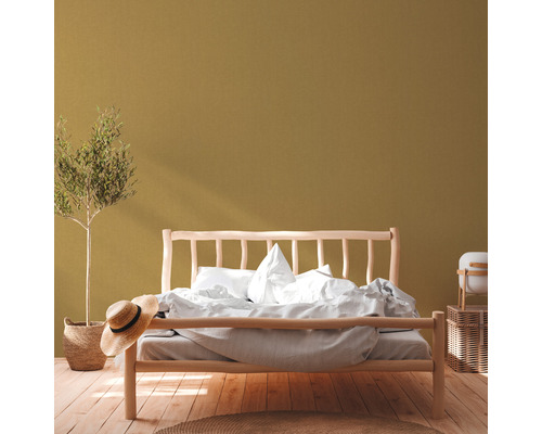 Schlafzimmer mit Holzbett, Zimmerpflanze, Strohhut und Holzboden