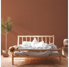 Helles Schlafzimmer mit Holzbett, Bettwäsche, Dekorationen und Zimmerpflanze