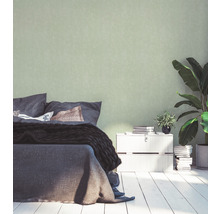 Schlafzimmer mit Bett, Nachttisch, Zimmerpflanzen und einfarbiger Tapete