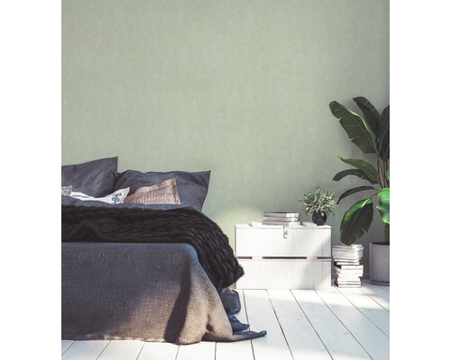 Schlafzimmer mit Bett, Nachttisch, Zimmerpflanzen und einfarbiger Tapete