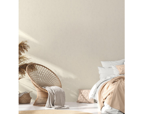 Helles Schlafzimmer mit Rattansessel, Bett und dekorativen Elementen für eine freundliche Atmosphäre.