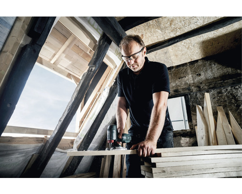 Ein Mann arbeitet in einem Dachgeschoss mit einer Stichsäge an einem Holzbrett.