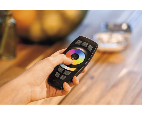 Eine Hand hält eine Fernbedienung zur Steuerung der Beleuchtung.