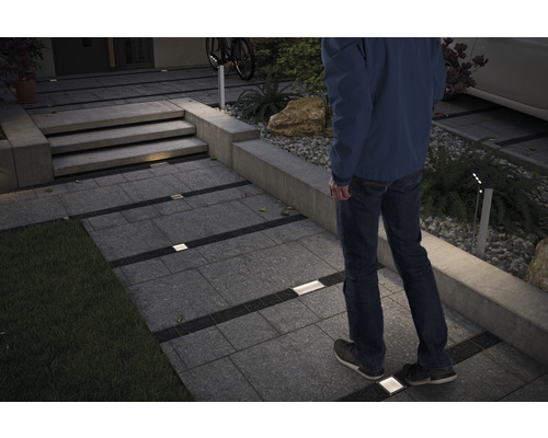 Chemin de jardin éclairé avec pavés et un homme