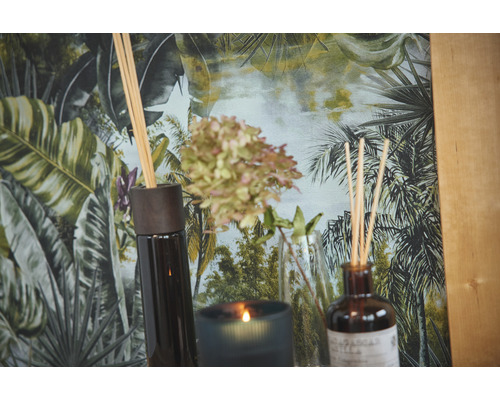 Diffuseurs de parfum d''intérieur et bougie parfumée devant un papier peint à motifs de jungle