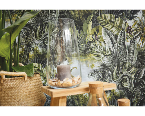 Décoration avec vase en verre, bougie et plantes sur plateau en bois devant un papier peint jungle