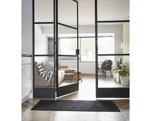 Zimmeransicht mit schwarzer Fussmatte und Glastür mit Stahlrahmen