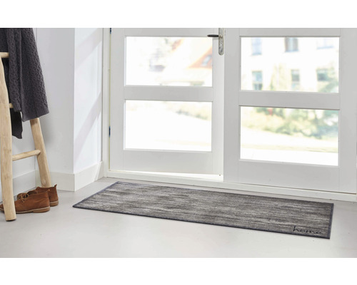 Scène avec un paillasson devant une porte, échelle, chaussures et vêtements