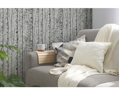 Wohnzimmer mit grauer Couch, Kissen, Decke und Tapete mit Birkenmotiv