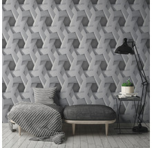 Wohnzimmer mit einer Wandtapete mit geometrischem 3D-Effekt, einem Sessel, einem Hocker und einer Stehlampe.