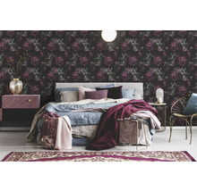 Chambre avec papier peint floral, lit et tables de chevet.