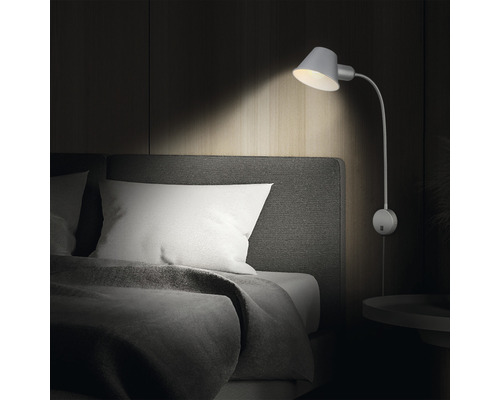 Wandleuchte aus Metall über einem Bett im Schlafzimmer.