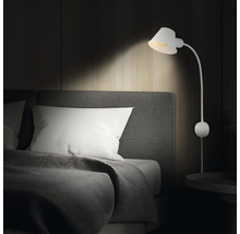 Chambre avec lit et applique murale blanche.