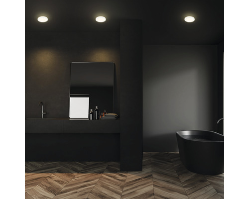 Dunkles Badezimmer mit Badewanne, Waschtisch und Deckenleuchten