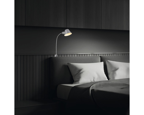 Schlafzimmer mit Bett und verstellbarer Wandleuchte