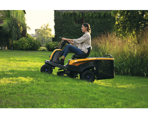 Femme conduisant un tracteur de pelouse sur une pelouse