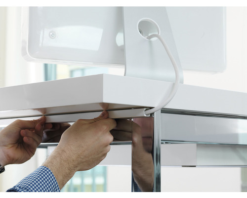 Person befestigt eine Kabelführung an einem Schreibtisch zur Kabelorganisation.