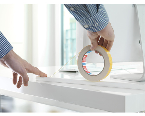 Doppelseitiges Klebeband wird auf einer weißen Oberfläche angebracht.