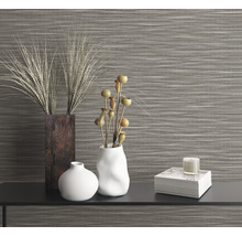 Dekoratives Arrangement mit Vasen, Pflanzen und Kerze vor einer Wandtapete