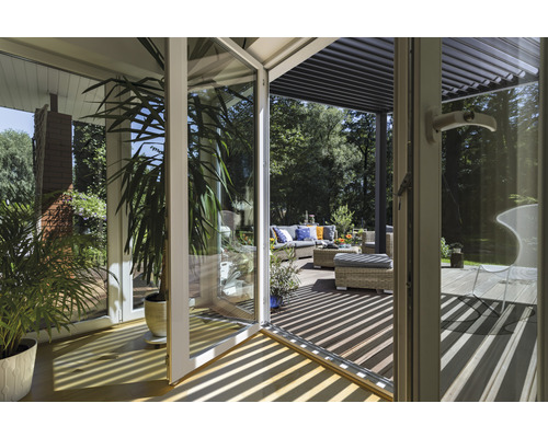 Vue à travers une porte en verre sur une terrasse avec des meubles de jardin et une pergola
