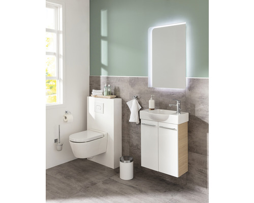 Salle de bains lumineuse avec toilettes, meuble sous-lavabo et miroir lumineux