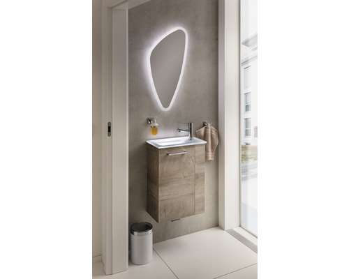 Salle de bains moderne avec lavabo, miroir éclairé et poubelle.