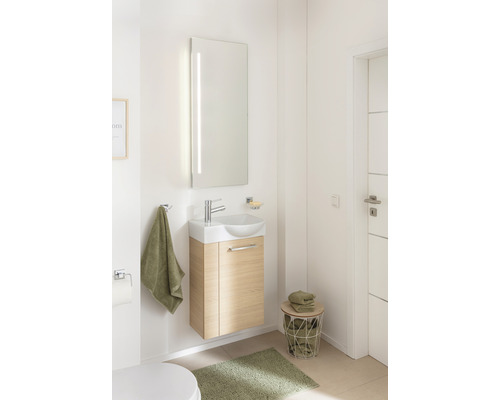 Salle de bain lumineuse avec lavabo, miroir, serviettes et rangements.