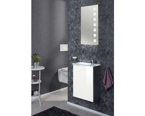 Salle de bains avec lavabo, miroir, toilettes et décoration dans des tons foncés.