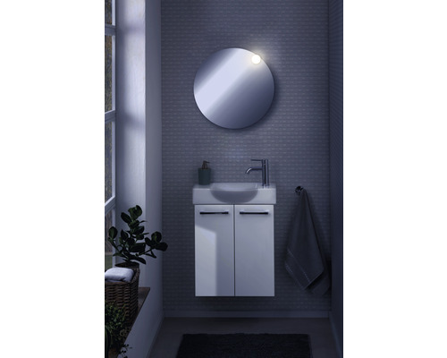 Badezimmer mit rundem Spiegel, Waschbeckenunterschrank, Armatur und Handtuchhalter