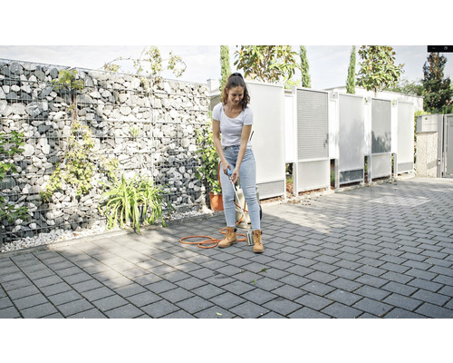Une femme utilise un brûleur à gaz pour lutter contre les mauvaises herbes sur les pavés à l''extérieur.